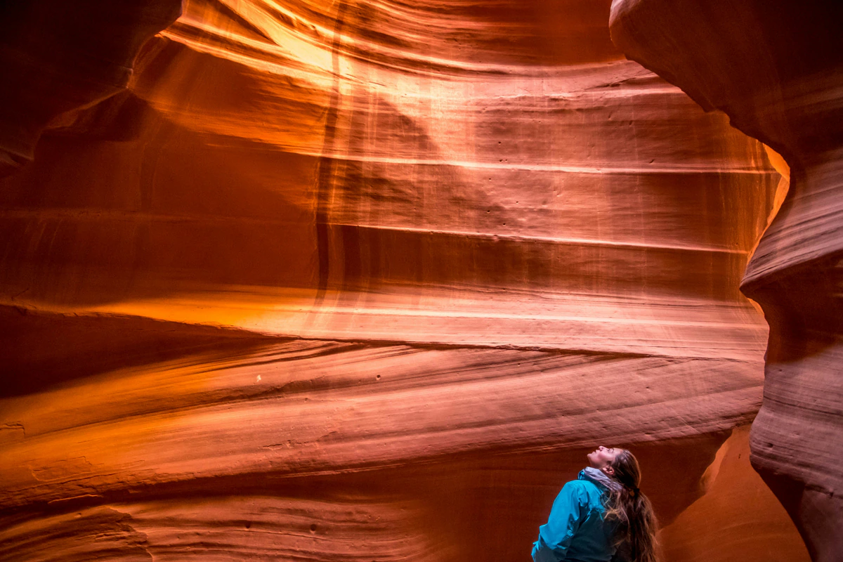 Visitor looking up at illuminated Antelope Canyon walls