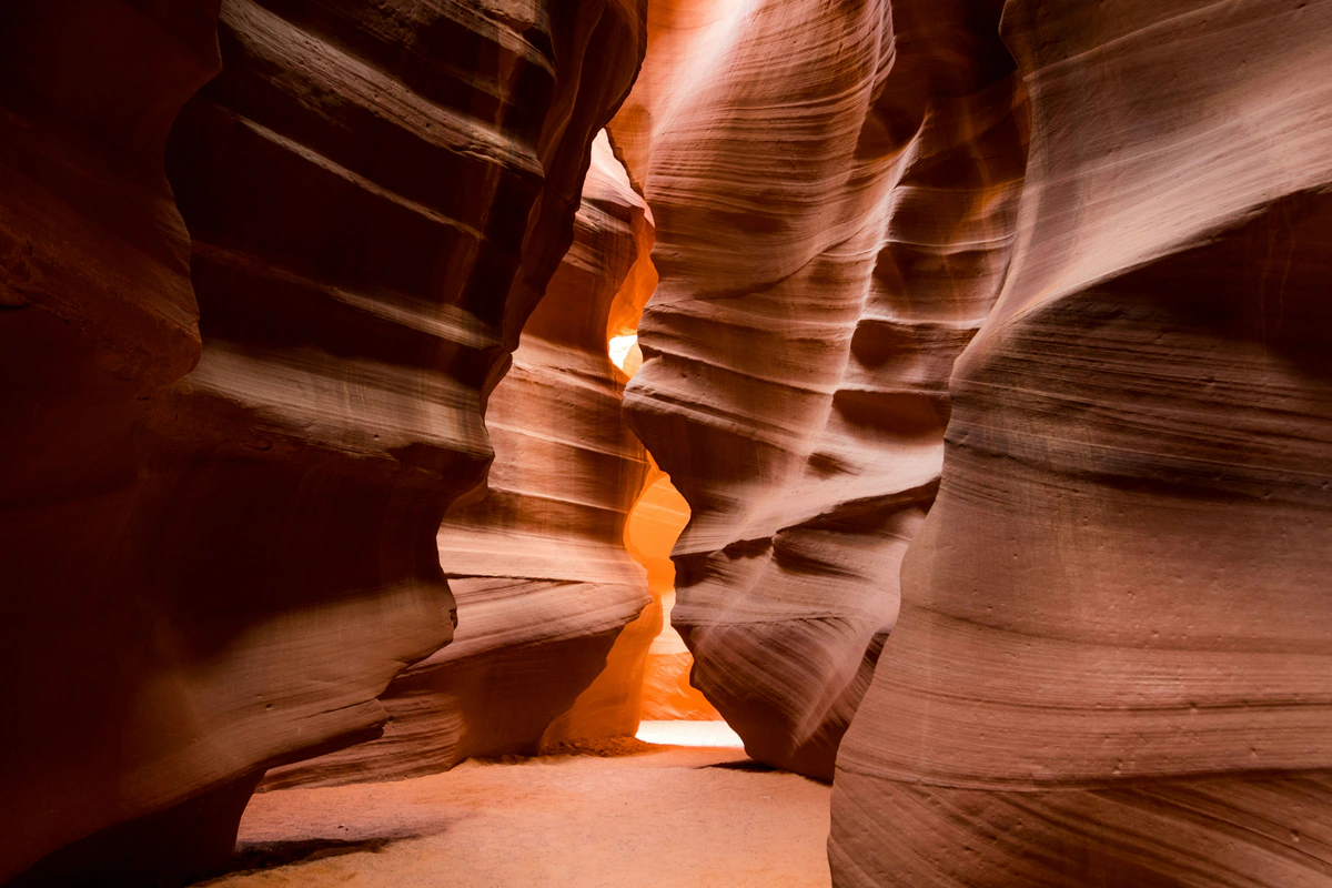 Wide sandy passage between layered Antelope Canyon walls